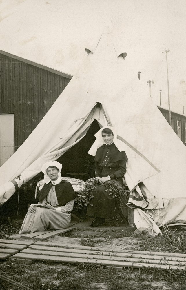 Sygeplejerske Eleanor Wibmer Jeffries og sygeplejerske Nellie Constance Morrice (til højre) uden for deres telt ved det 3. australske felthospital med blomster plukket på Sommes bred, ca. juni 1917 af Australian Photographer