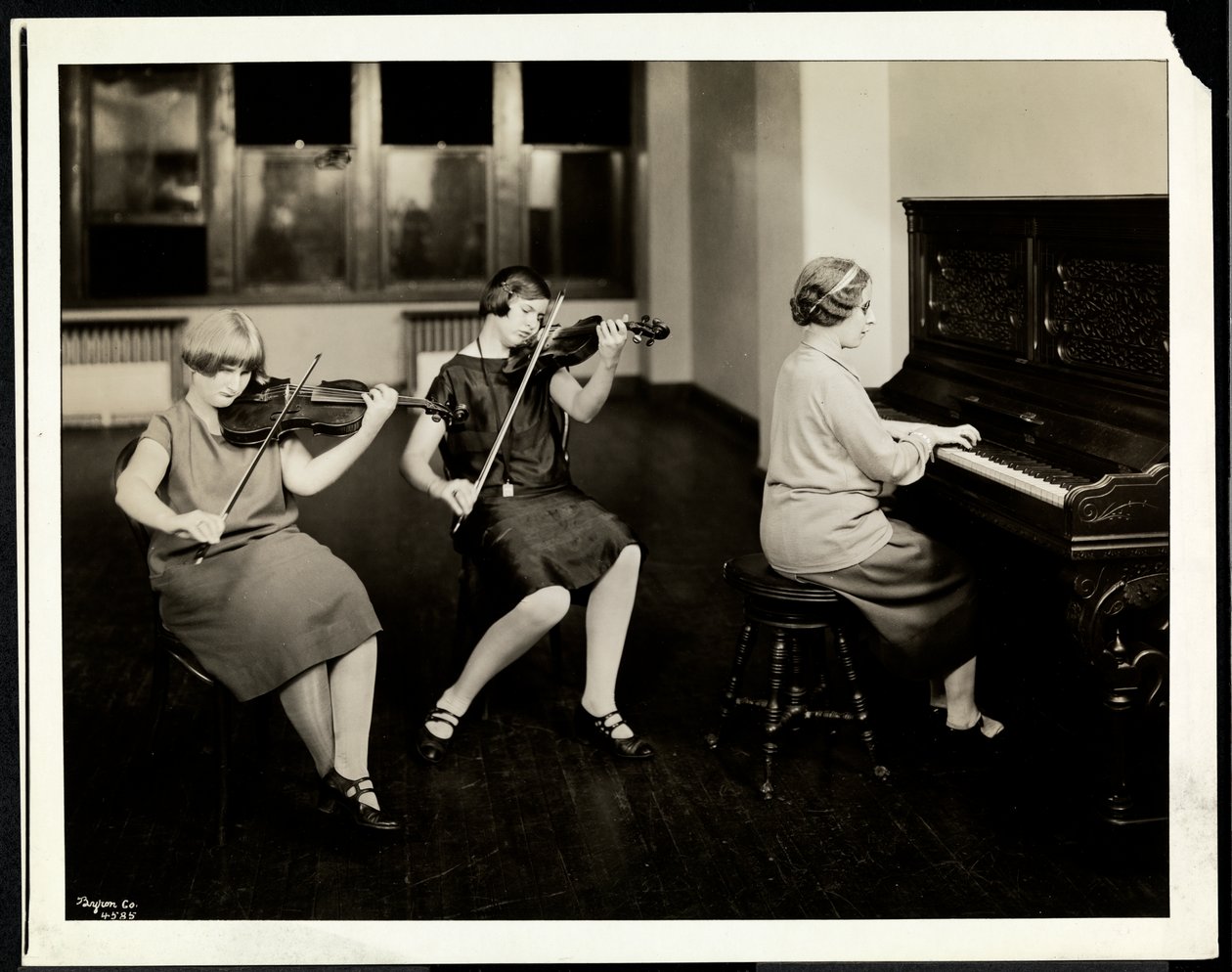 Gruppe på tre unge blinde kvinder, en ved klaveret, to spiller violiner, ved New York Association for the Blind, 111 East 59th Street, New York, 1926 (sølv gelatinetryk) af Byron Company
