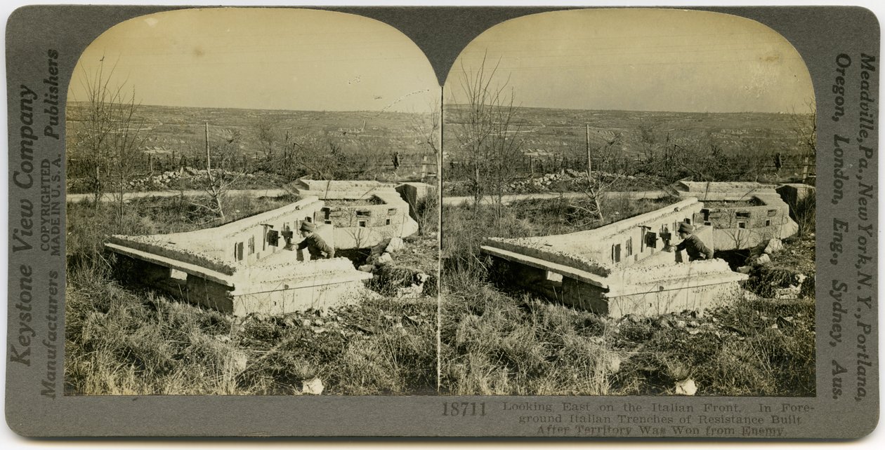 Horisontalt sepia -stereokort, der viser en uniformeret mand, der står bag et sæt betongrave i et åbent felt. Keystone Stereograf nummer 18711. Titlen lyder af Keystone View Company