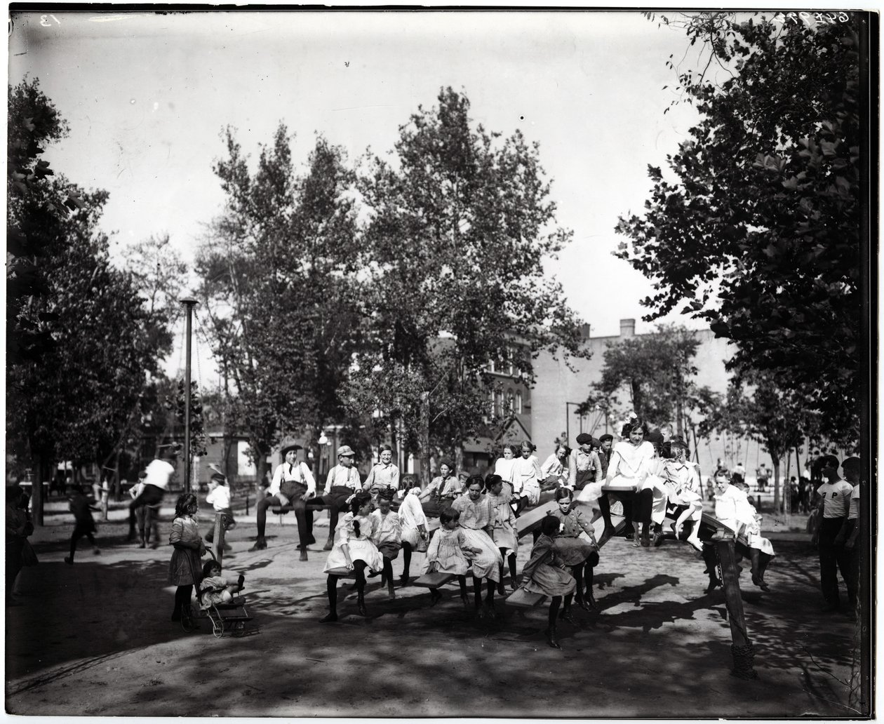 Vandret, sort / hvidt fotografi, der viser børn, der leger på vipper i en uidentificeret park af Unknown