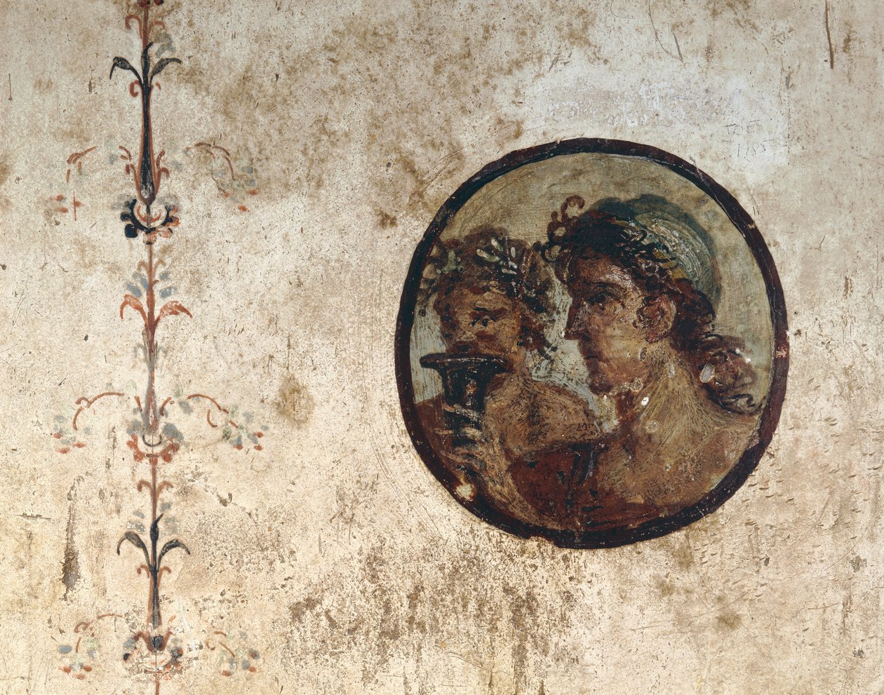 Interiør af et værelse med vægfresker fra den romerske periode, stil III, i huset til Corieo Tiburtino i Pompeji: del af en vinstok og en tondo med to mandlige hoveder af Unknown