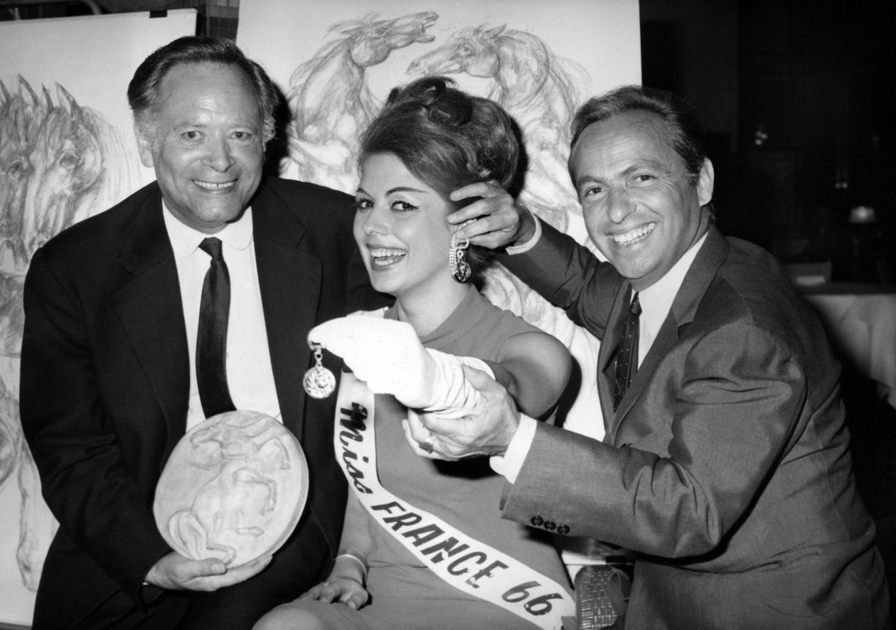 Rene Bollinger (Venstre) og Guy Lux Entourent Monique Boucher "Miss France" til hvem de lige afleverer en nøglering "Talisman Du Turfiste" under åbningen af Bollingers Canvas den 12. juli 1966 af Unknown