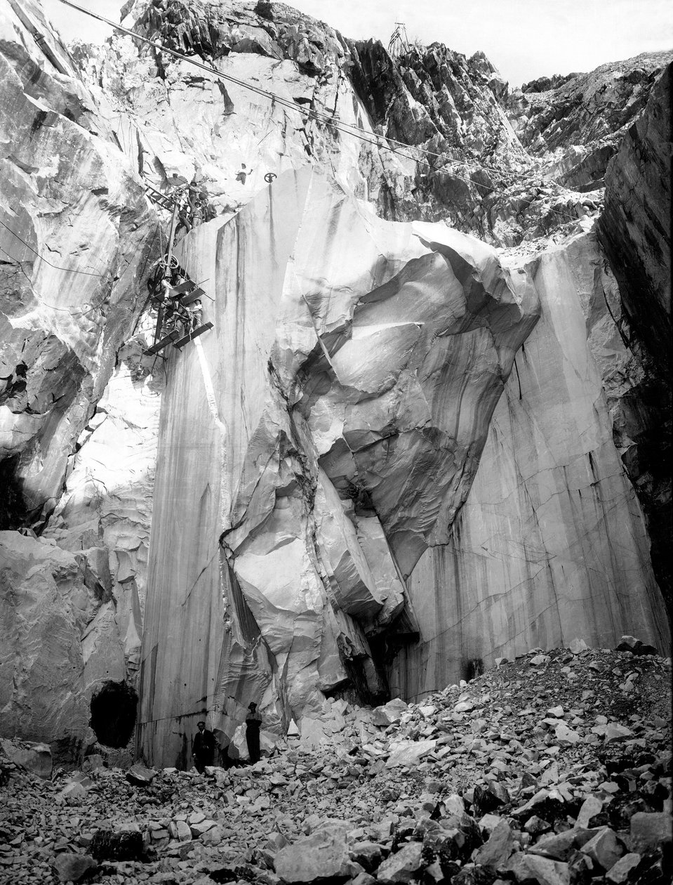 Gravemaskiner på arbejde langs en stejl mur i et marmorbrud i Apuan Alperne, Toscana. (s/h foto) af A. Corsini