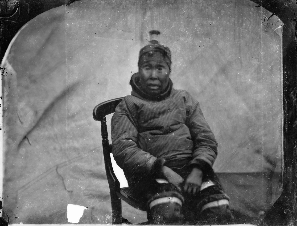 En ældre inuk-kvinde sidder i en stol af Admiral Edward Augustus Inglefield