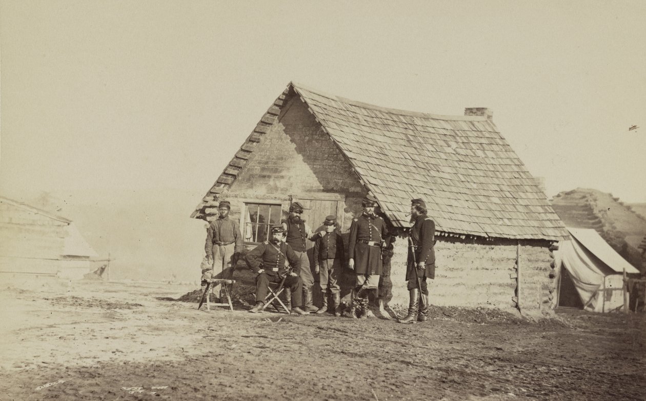 En gruppe soldater og to unge mænd, den ene en afroamerikaner, står uden for bjælkehyttekvarteret, 1861-65 af American Photographer