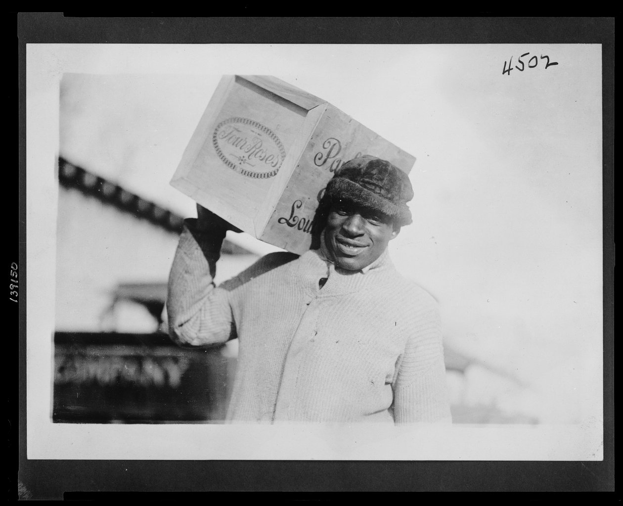Afroamerikansk mand med en kasse med "Four Roses" whisky på skulderen, muligvis konfiskeret af US Internal Revenue Bureau af American Photographer