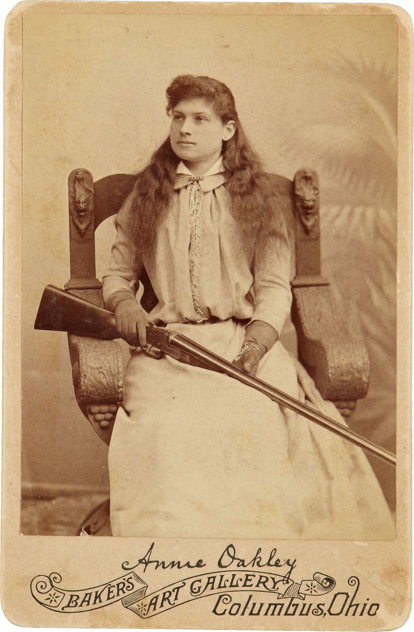 Annie Oakley: Annie Oakley:. Her sidder den legendariske skarpskytter temmelig nedslående i en massiv stol i renæssancestil, et haglgevær hviler i hendes skød. Hendes sarte feminine træk og strømmende hår modsiger hendes robuste udendørsbillede ©Buyenlarge af American Photographer
