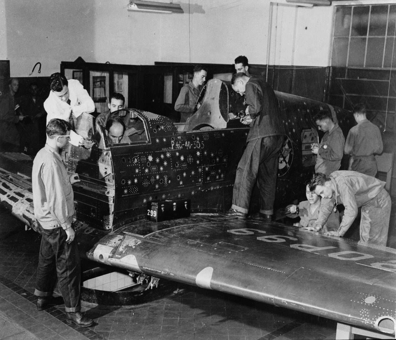 Soldatelever arbejder på "Flying Patch", et Curtiss "Warhawk" jagerfly uden motor eller hale, med simulerede skudhuller og patches, ca. 1942 af American Photographer