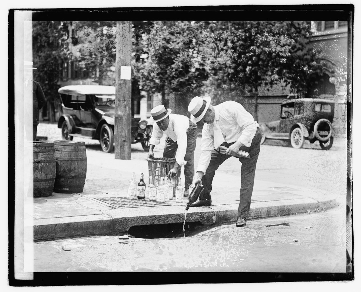 To mænd hælder spiritus i stormafløb, 8. juli 1921 (s/h-foto) af American Photographer