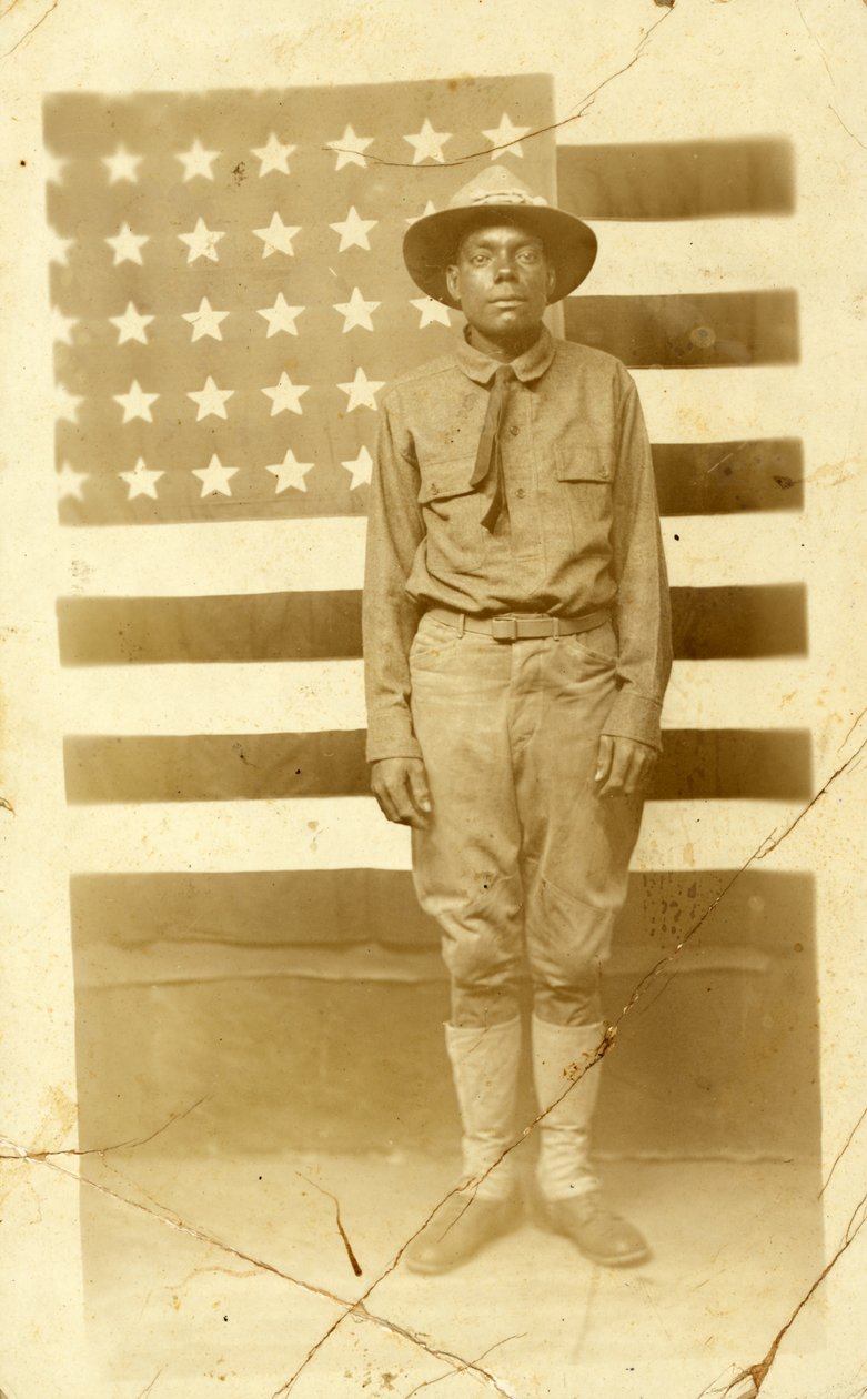 Soldat fra første verdenskrig med amerikansk flag i baggrunden, 1914-18 af American Photographer