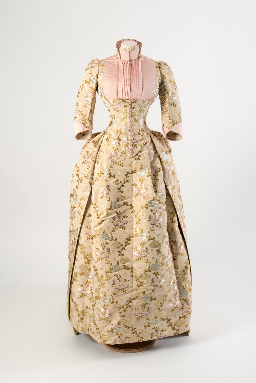 Kjole af lysebrun silke vævet med et design af lilla, blå og gule blomster og grønne blade, lys pink ribbet silkeoverdel og manchetter af American School