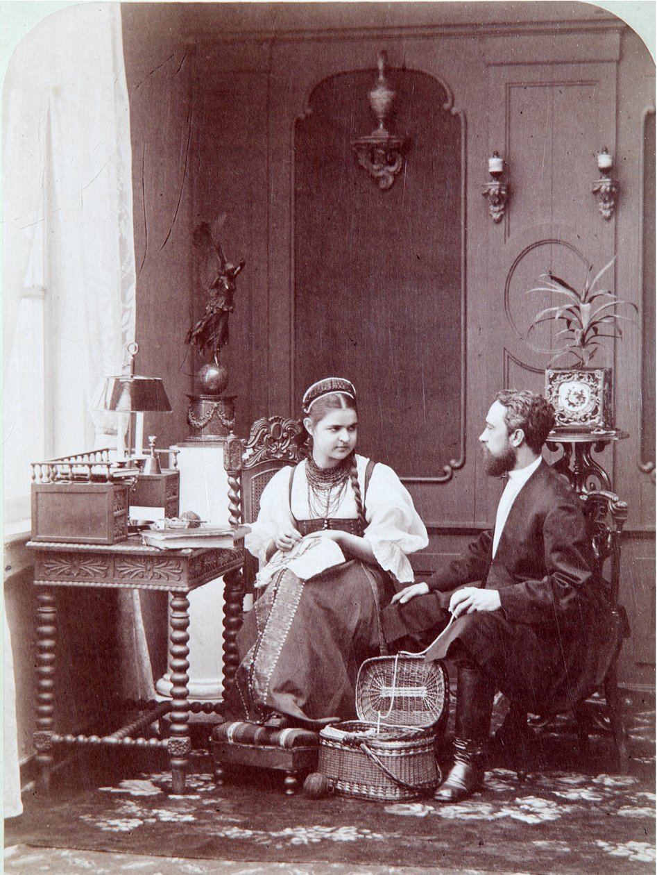 Komposition à la russe: interiør af en russisk bolig med mand og kvinde, der broderer og klædt i traditionelle dragter. Fotografi af Andrei Osipovich Karelin (1837-1906), år 1870-1880. Statens Historiske Museum, Moskva Komposition på russisk. Albumin af Andrei Osipovich Karelin