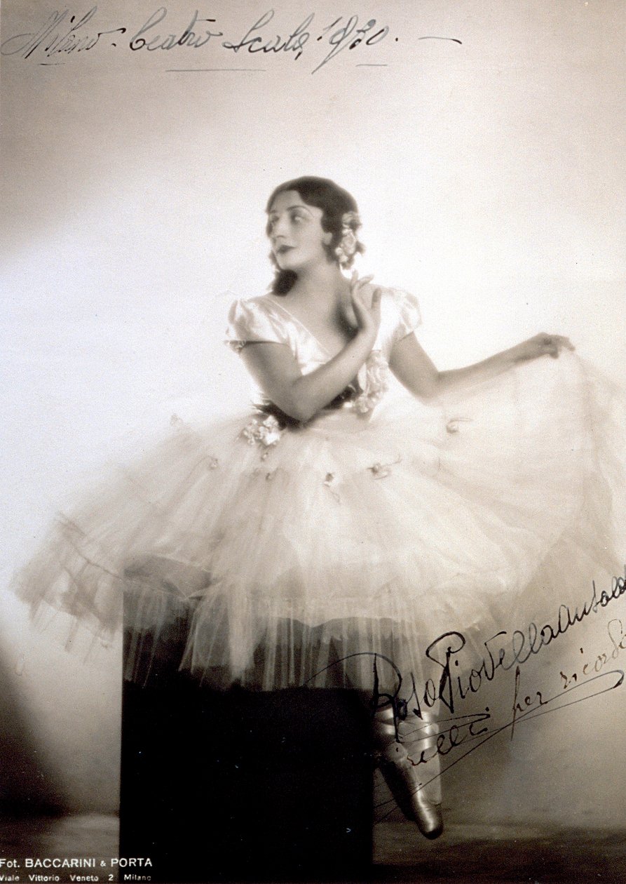 Portræt af den klassiske ballerina Rosa Piovella Ansaldo, i tutu og balletsko. Hun sidder foran med ansigtet vendt til den ene side. Stofroser dekorerer hendes beklædningsgenstand og omhyggeligt klædt hår (Milan, Teatro alla Scala) (s/h foto) af Baccarini and Porta