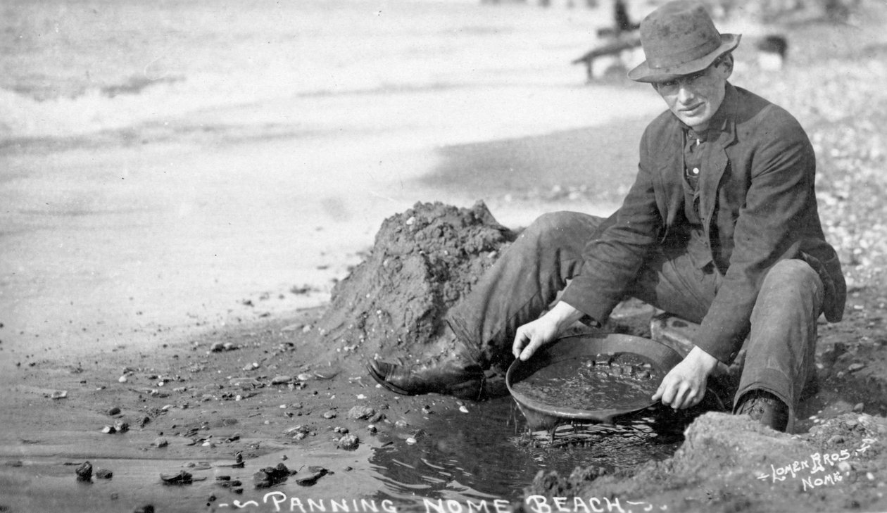 Mand, der panorerer guld på stranden, Nome, Alaska, ca. 1910 (s/h-billede) af Brothers Lomen