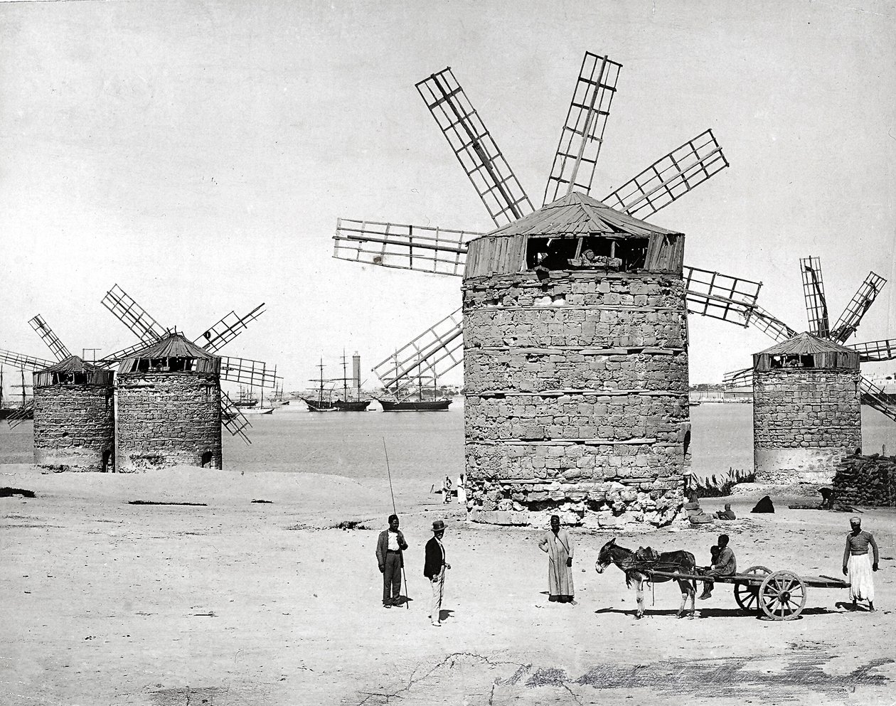 Vindmøller ved Middelhavet i Alexandria, Egypten. Foran poserer nogle egyptere med en lille vogn. af Brothers Zangaki