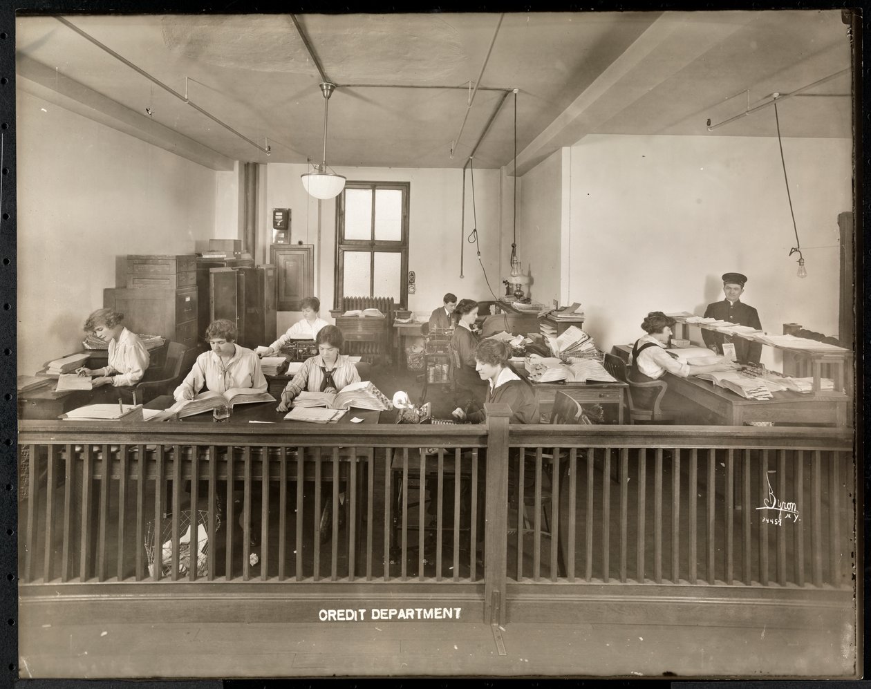 En mand og kvinder, der arbejder på kreditkontoret hos Mantle Lamp Co. of America, New York, 1915-16 (sølv gelatinetryk) af Byron Company
