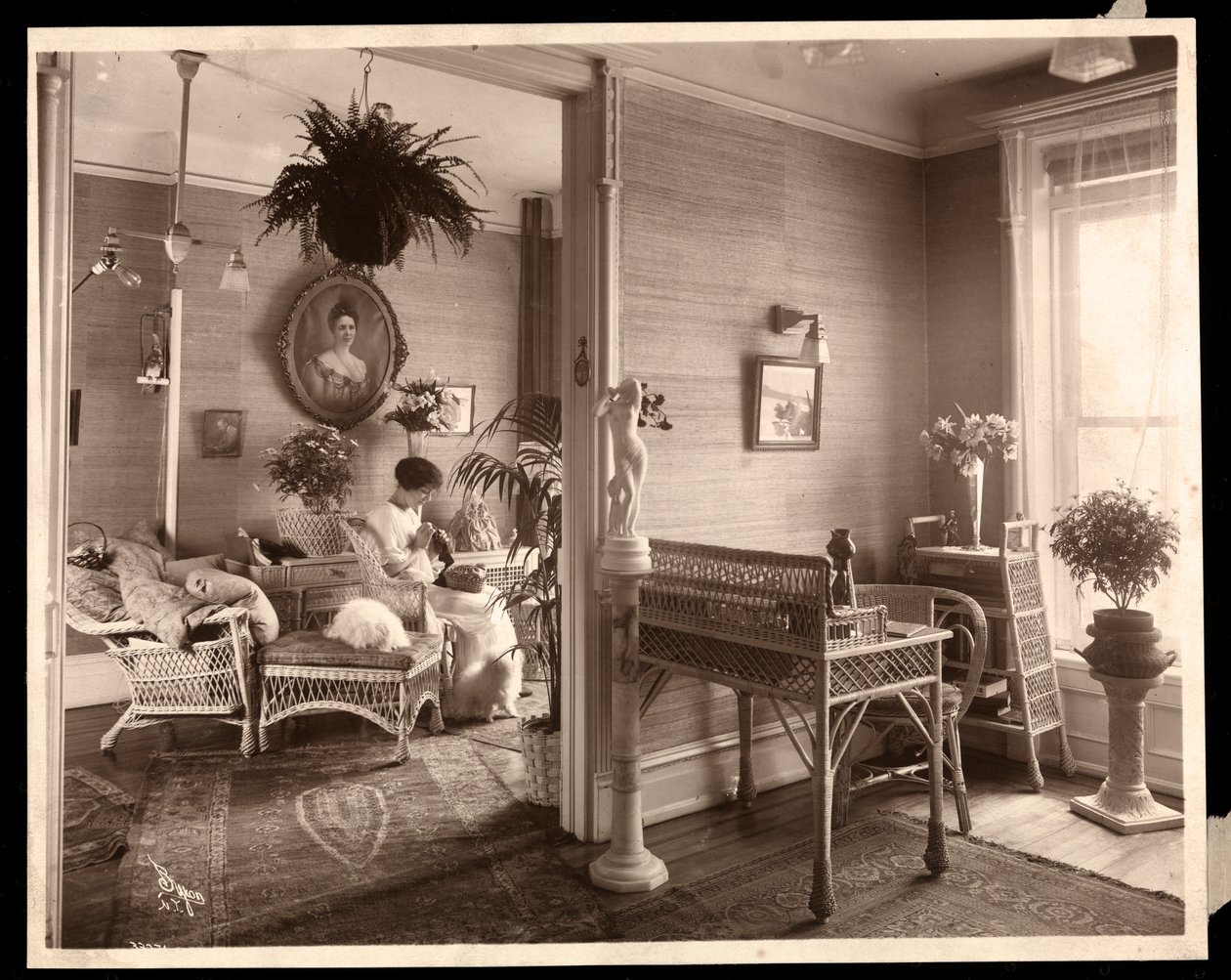 En kvinde, der laver et nålearbejde i en stue, 1914 eller 1915 (sølv gelatinetryk) af Byron Company