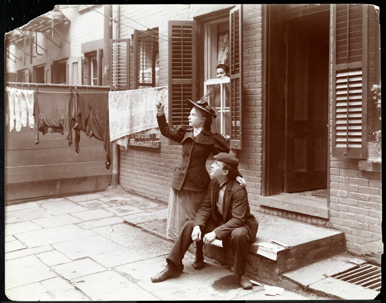 En ung mand og kvinde poserede ved et dørtrin, New York, 1896-98 (sølv gelatinetryk) af Byron Company