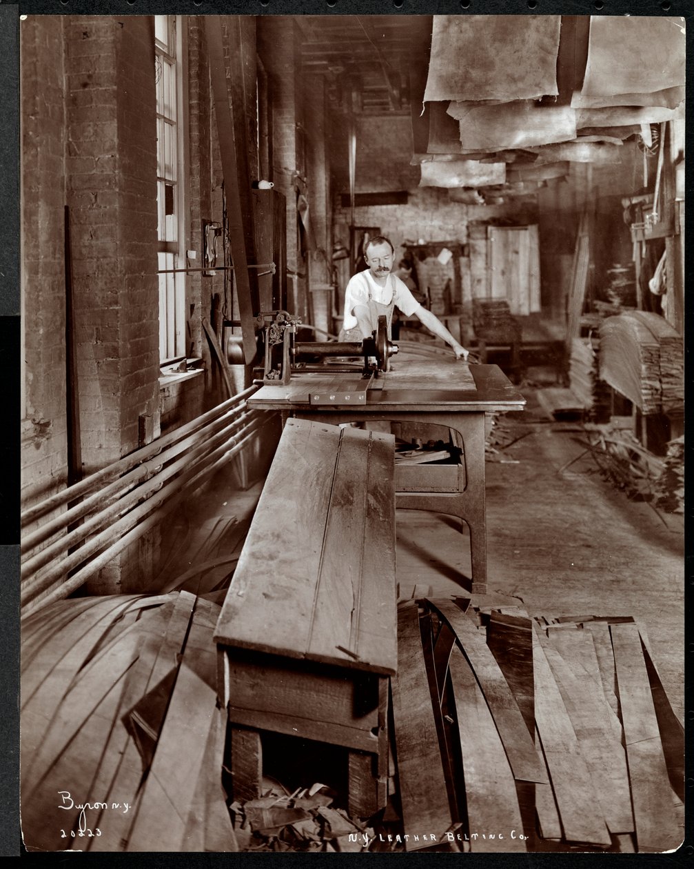 Indvendigt billede af en mand, der arbejder med læder på New York Leather Belting Co., New York, 1905 (sølv gelatinetryk) af Byron Company