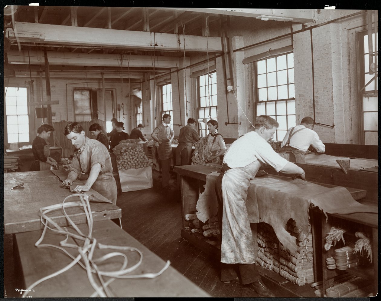 Indvendigt billede af mænd og kvinder, der arbejder med læder på New York Leather Belting Co., New York, 1906 (sølv gelatinetryk) af Byron Company