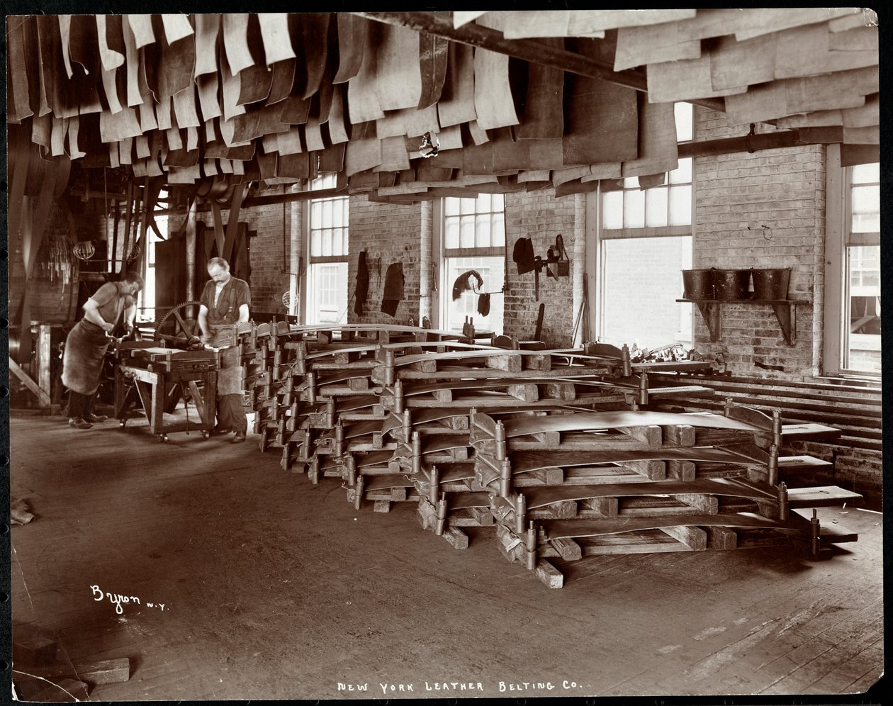 Indvendigt billede af to mænd, der arbejder med læder på New York Leather Belting Co., New York, 1905 (sølv gelatinetryk) af Byron Company