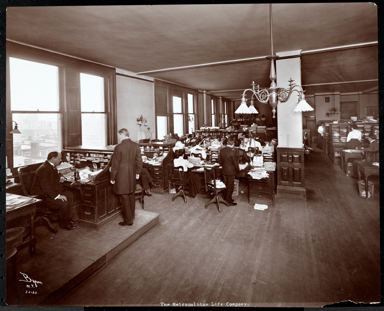 Mænd og kvinder arbejder ved skriveborde i et kontor hos Metropolitan Life Insurance Co. på 23rd Street og Madison Avenue, New York, 1907 (sølvgelatineprint) af Byron Company