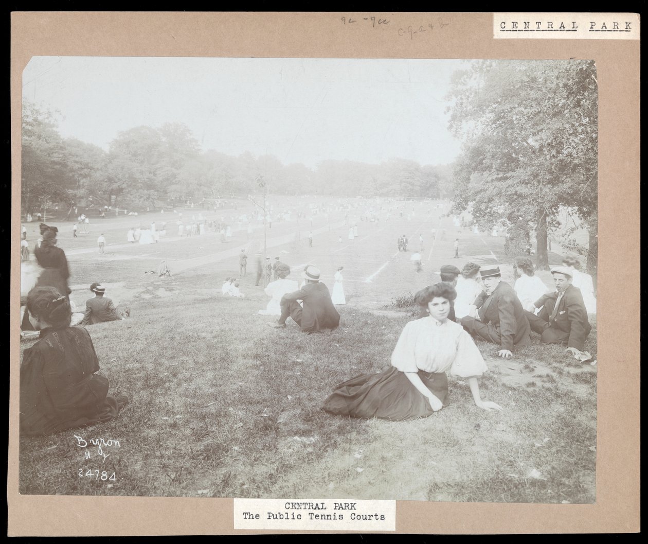 Udsigt over mænd og kvinder siddende på græs for at se på tennis på græsplæne i Central Park, New York, ca. 1917 (sølvgelatineprint) af Byron Company