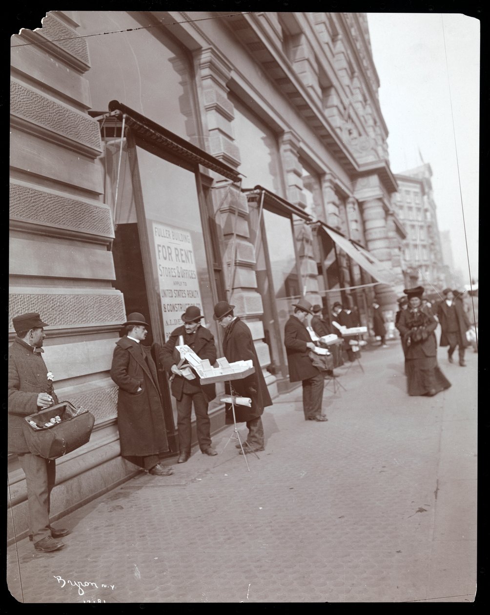Udsigt over kræmmere, der sælger legetøj og andre genstande foran Fuller eller Flatiron Building på Broadway, 5th Avenue og 23rd Street, New York, ca. 1895 (sølv gelatinetryk) af Byron Company