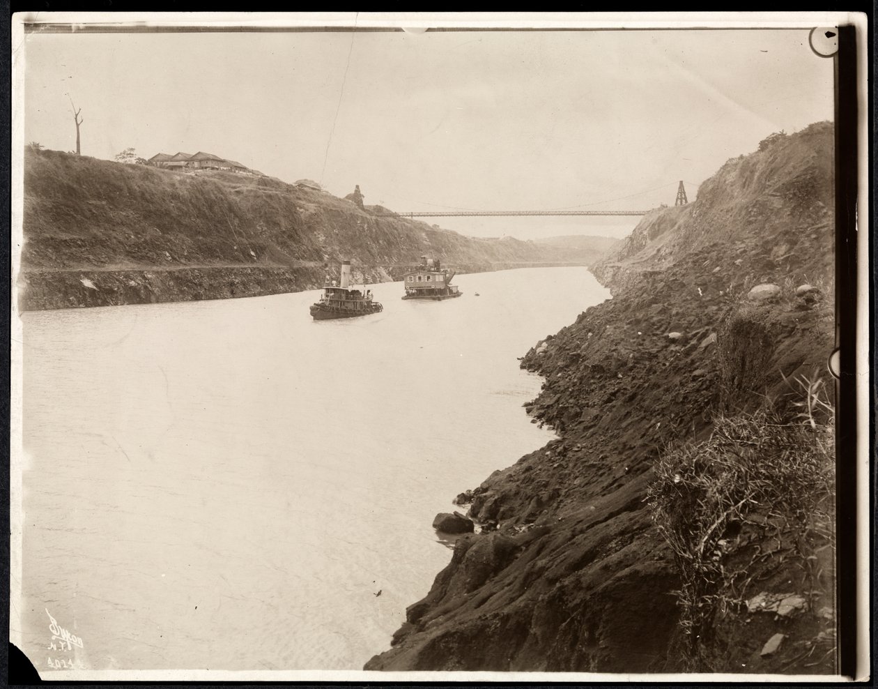 Udsigt over to både i Panamakanalen under dens konstruktion med en hængebro bagved, 1913 (sølv gelatinetryk) af Byron Company