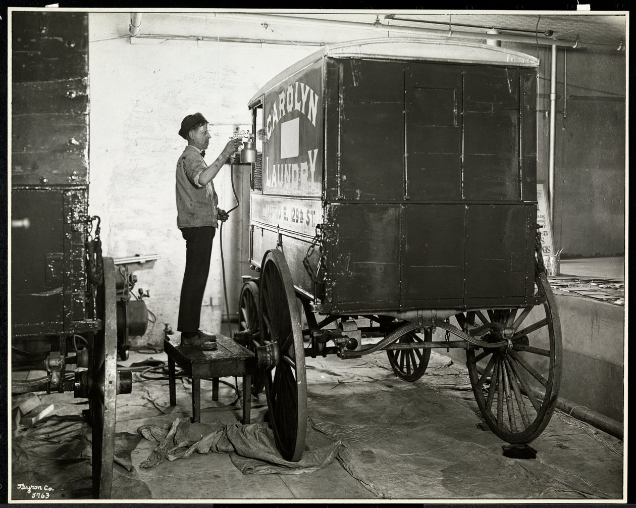 En mand spraymaler en vogn fra Carolyn Laundry på 111 East 128th Street, East Harlem, New York, 1929 (sølvgelatineprint) af Byron Company