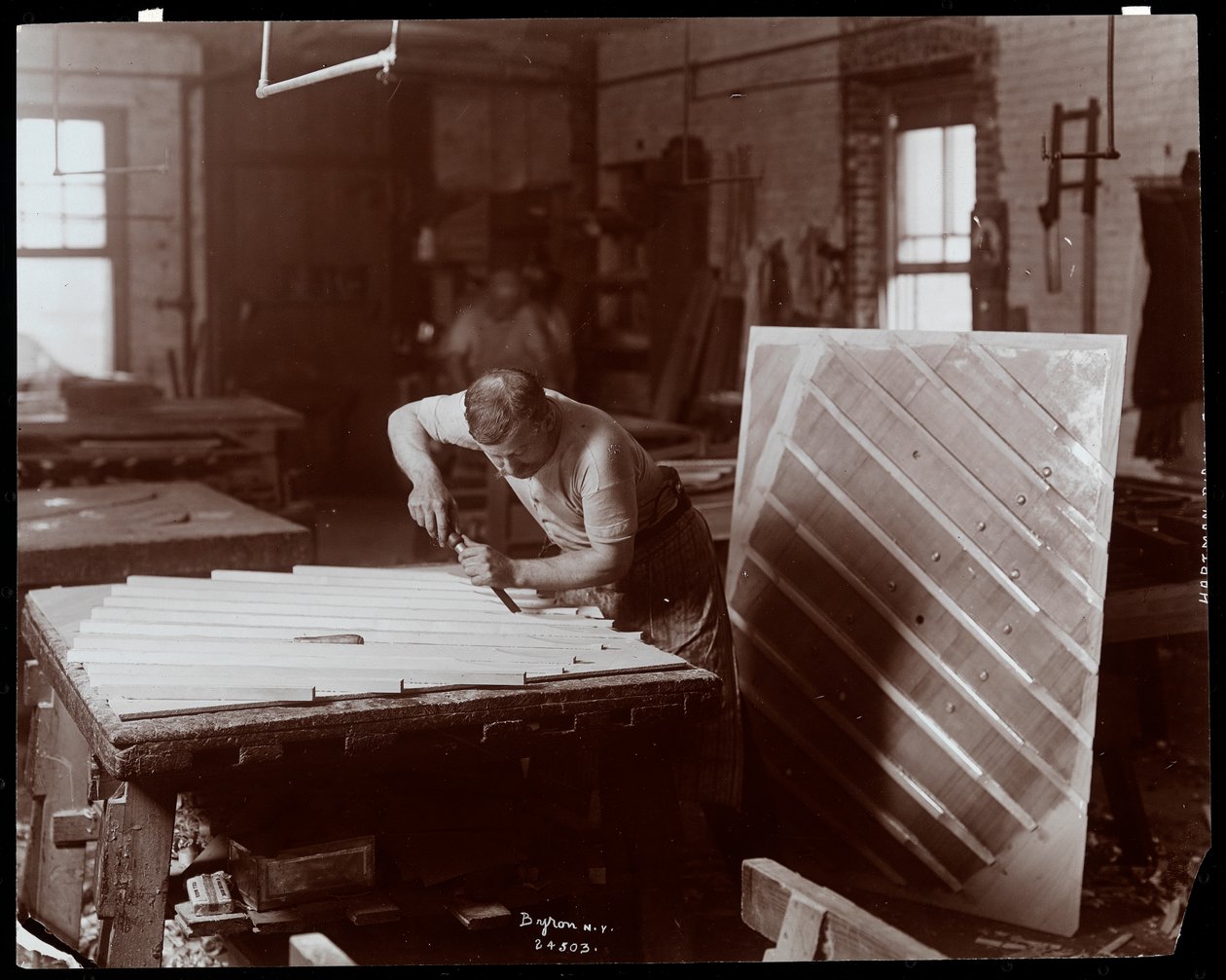 Mand arbejder i Hardman, Peck und Co. klaverfabrik, New York, 1907 (sølvgelatineprint) af Byron Company