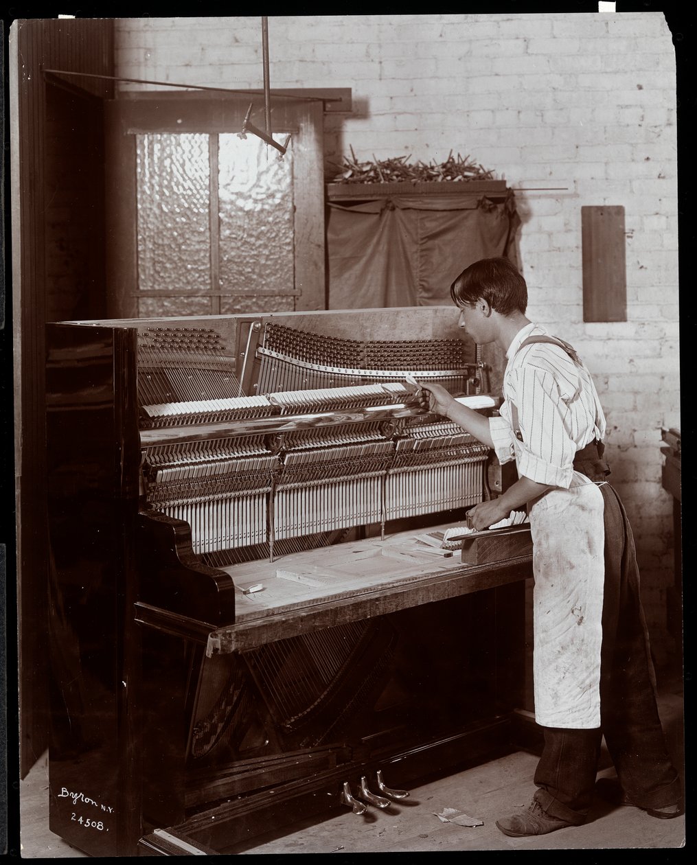 Mand, der arbejder i Hardman, Peck und Co. klaverfabrikken, New York, 1907 (sølv gelatinetryk) af Byron Company