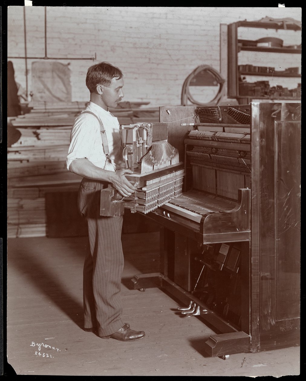 Mand, der arbejder i Hardman, Peck und Co. klaverfabrikken, New York, 1907 (sølv gelatinetryk) af Byron Company