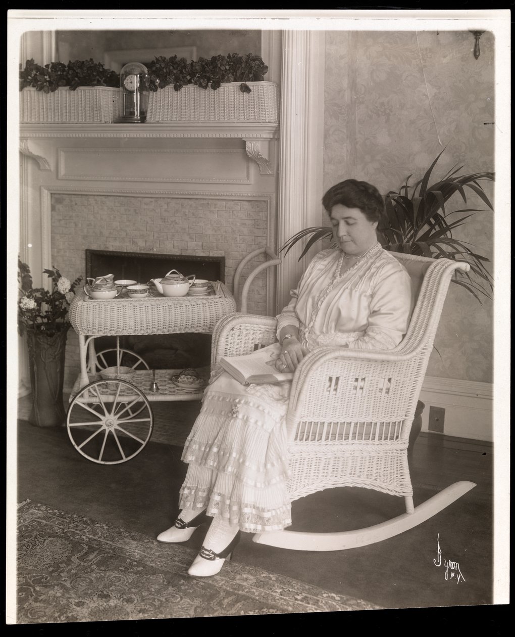 Mrs. Howard sad med en bog i en gyngestol i sit hjem på 200, 5th Avenue, New York, 1915-6 (sølv gelatinetryk) af Byron Company