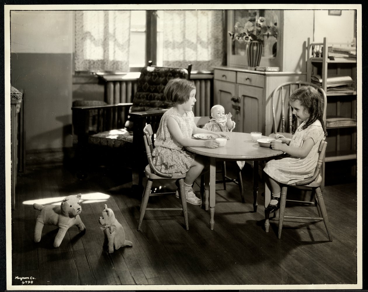 To blinde synshandicappede piger spiser ved et lille bord med en dukke hos New York Association for the Blind, 111 East 59th Street, New York, 1933 (sølv gelatinetryk) af Byron Company