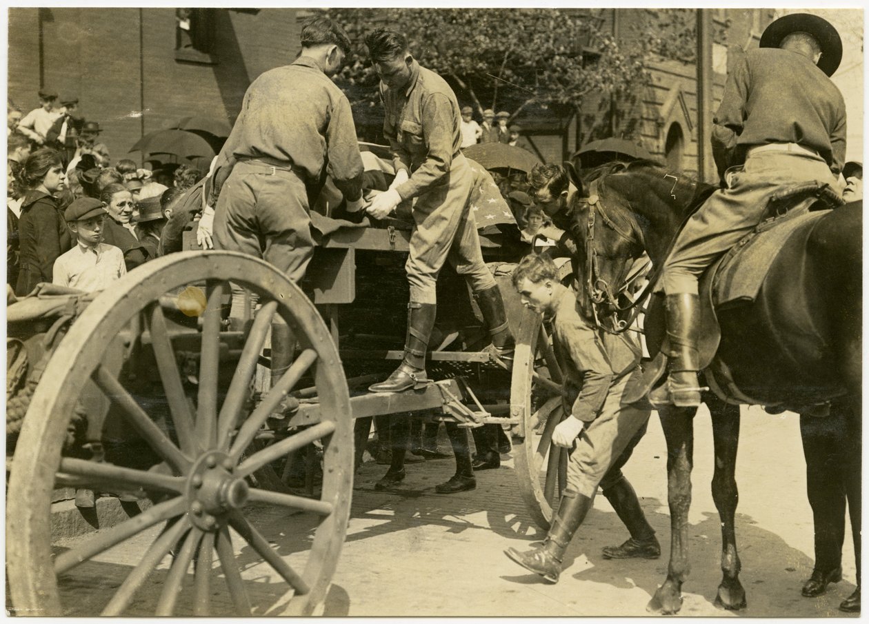 Horisontalt sepia -fotografi, hvor uniformerede mænd læser en genstand, der er draperet i det amerikanske flag, muligvis en kiste, ud af en åben vogn. En skare mennesker ser på fra fortovet af Carl Michel