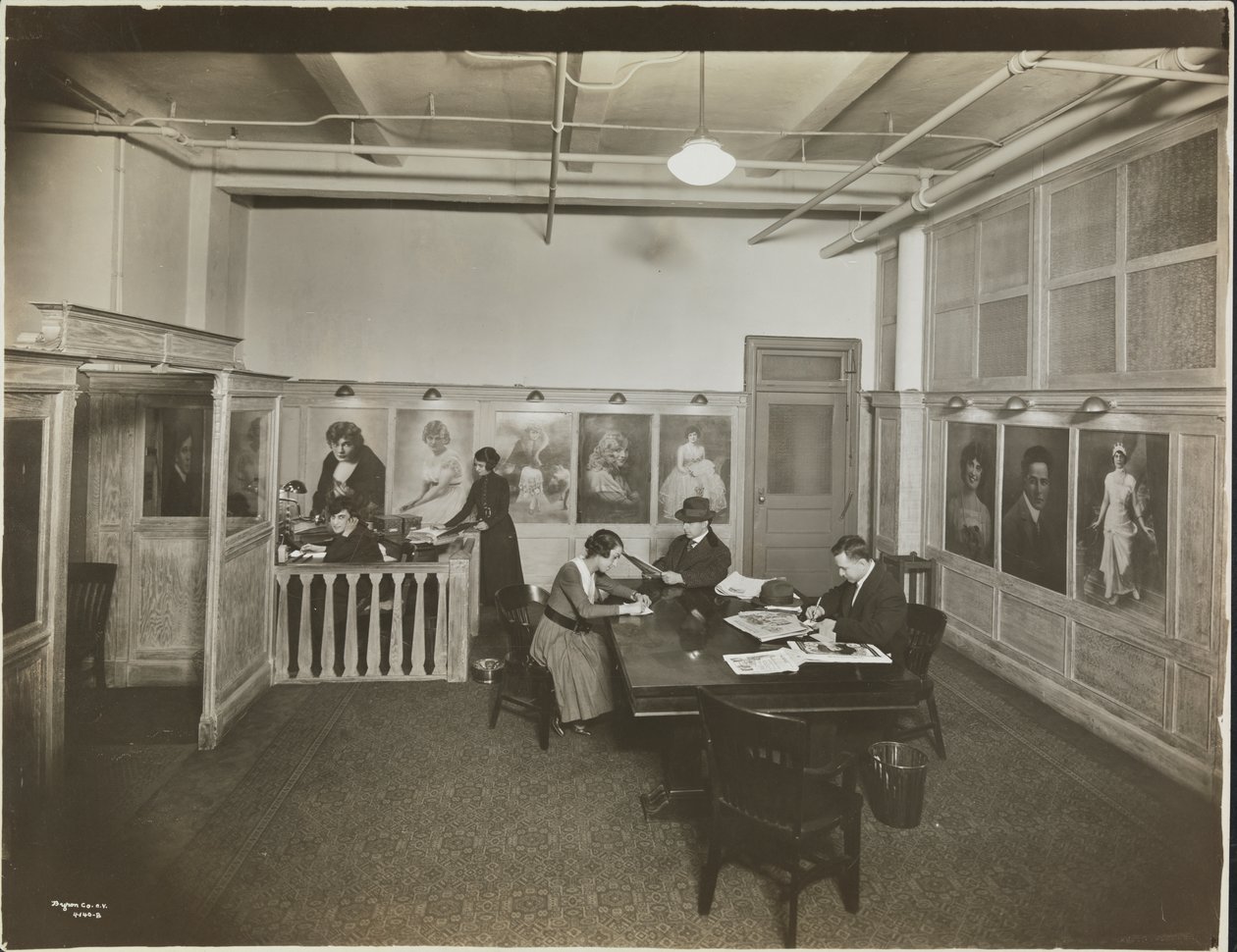 Hovedkontor/receptionslokale på Mutual Film Co. med sekretær ved skrivebordet, folk ved et bord, der læser, og portrætter på væggen, New York af Company Byron