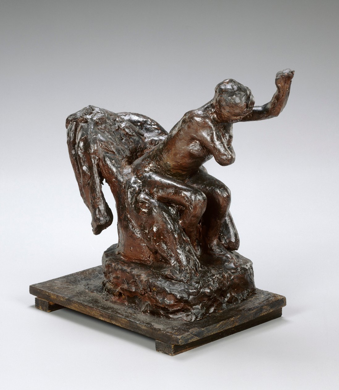 Kvinde, der sidder i en lænestol, tørrer sin venstre armhule, ca. 1890