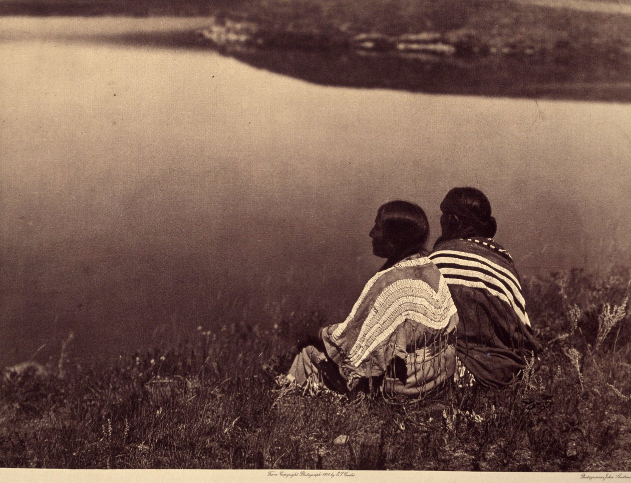 En ledig time - Et øjebliks ro: Piegan-indianere, der sidder på kanten af en vandmasse. Foto taget fra bind 6 af encyklopædien udgivet af Edward S. Curtis (1868-1952) om indianerne i Nordamerika, med et forord af Theodore Roosevelt. B af Edward Sheriff Curtis