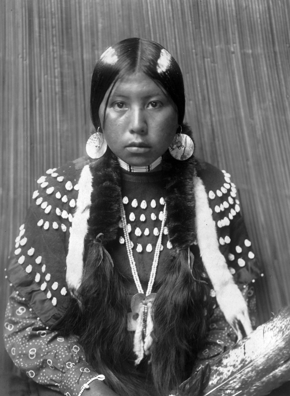 Kalispel indisk kvinde, hvide striber malet på håret, øreringe med skalskiver, iført tæppekjole dekoreret med elgens tænder, ca. 1910, foto Edward S. Curtis af Edward Sheriff Curtis