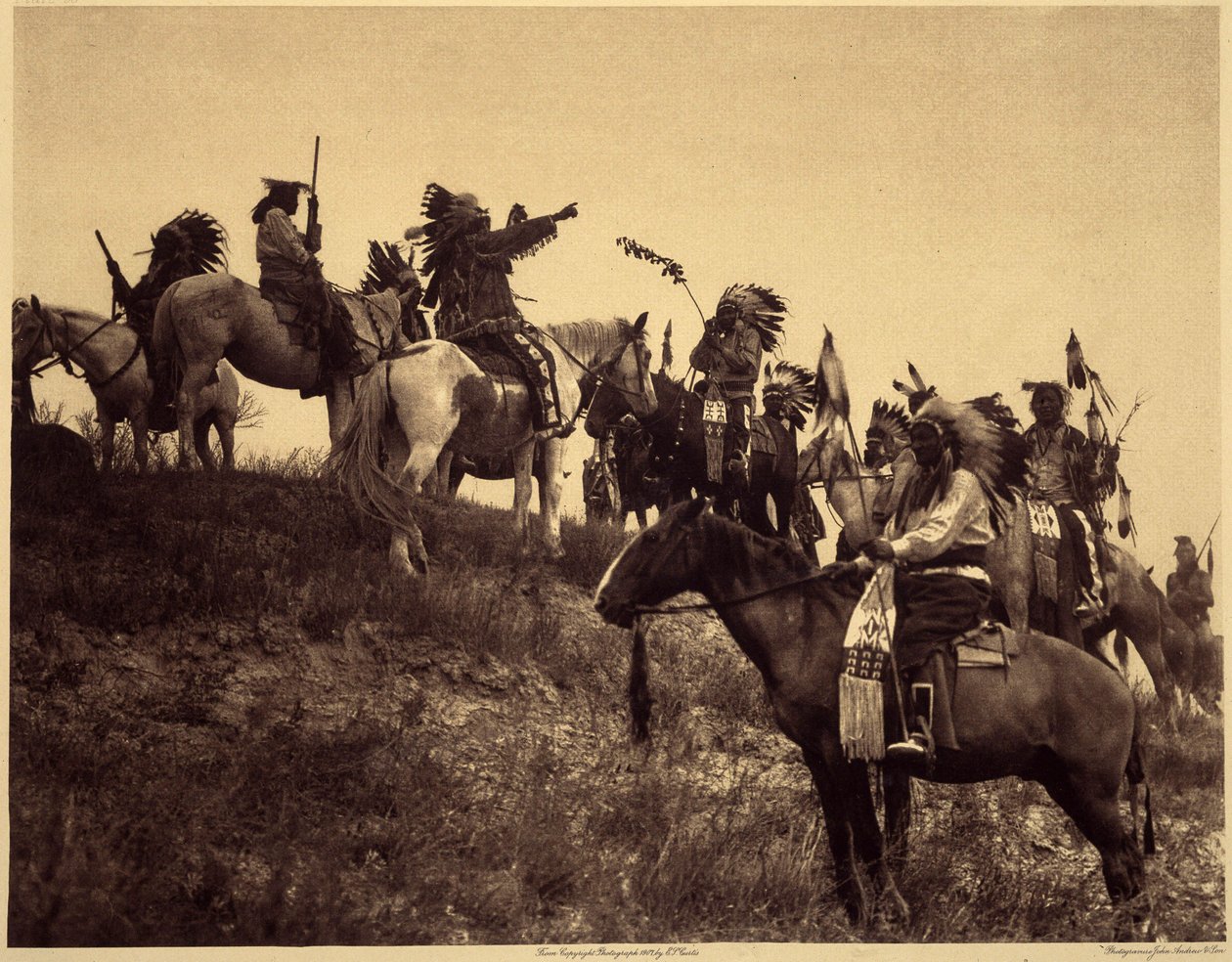 Planlægger et raid. Indianerne, i deres imponerende typiske kostumer, mødes i yderst maleriske grupper. Dette er en troppe fra Sioux Ogalala (Oglala), på en bakke med udsigt over Wounded Knee Valley i Pine Ridge Reserve, South Dakota. Foto tak af Edward Sheriff Curtis