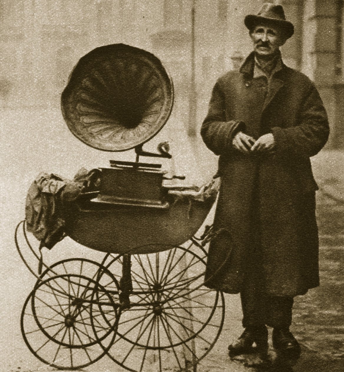 En gadehandler underholder med en grammofon, transporteret i barnevogn (sepia foto) af English Photographer