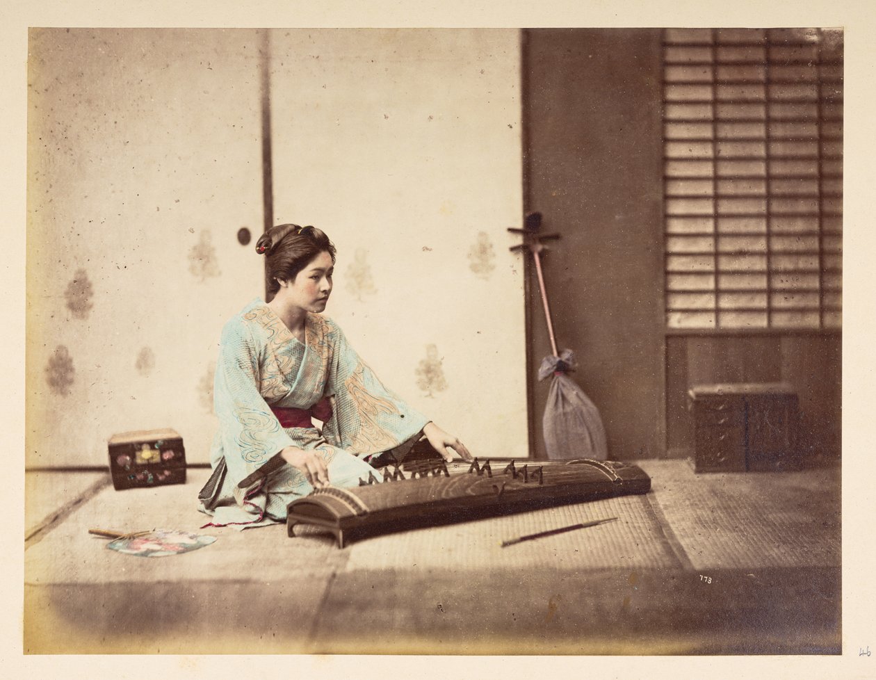 Syngende piger [Japan], Studieportræt af en ung japansk kvinde siddende på en tatamimåtte og spiller et strengeinstrument,  Fotograf: Ukendt  Lucas Collection: Fotografisk optagelse af Charles James og Morton P, Lucas