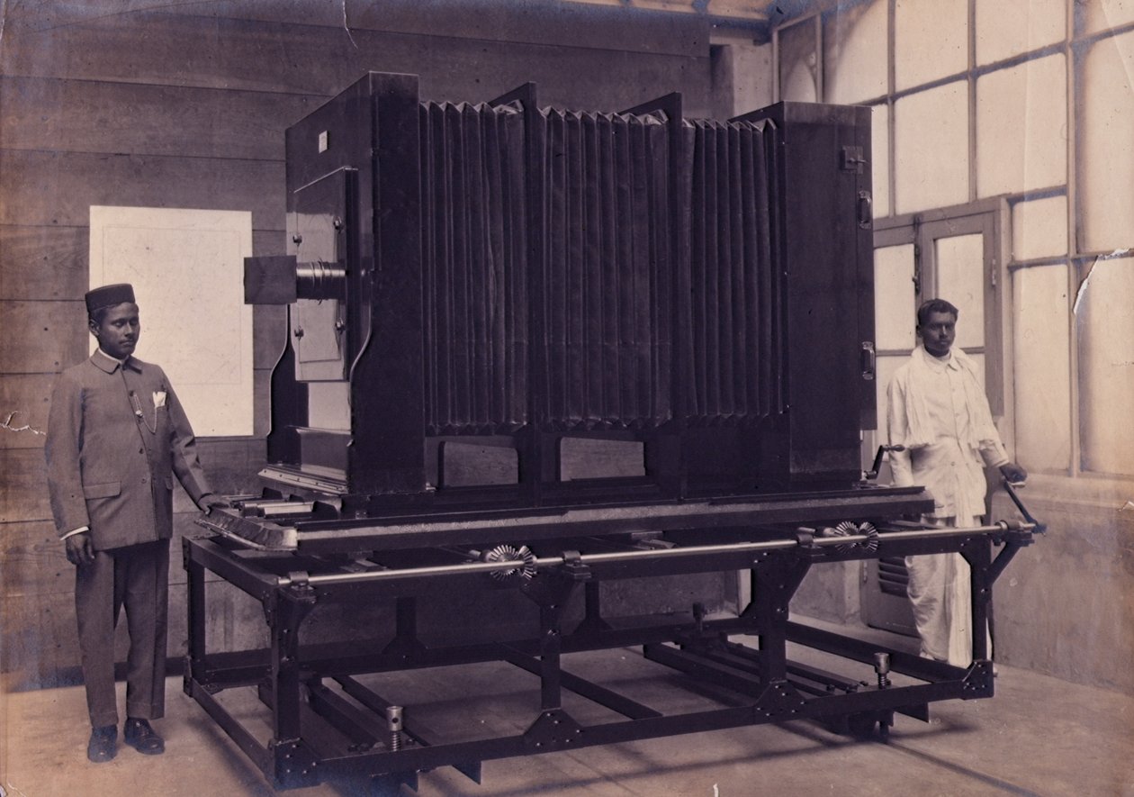 To indiske assistenter stående ved siden af det massive kamera i Photographic Department of the Survey of India, ca. 1911 (foto) af English Photographer