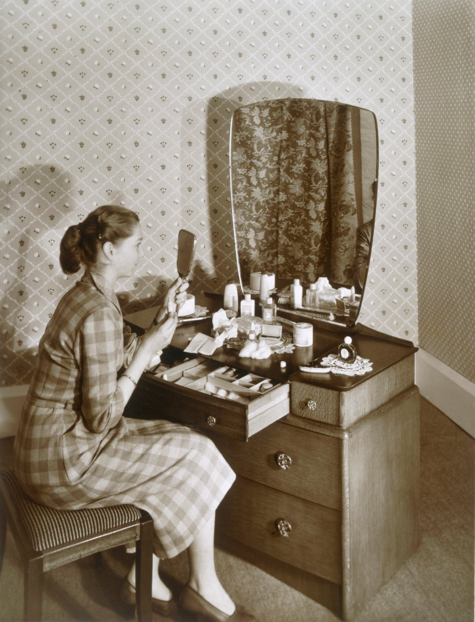 Kvinde ved hendes toiletbord, c1955. af English Photographer