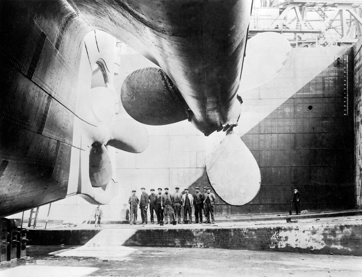 Arbejdere stående under en af propellerne på Titanic, 31. maj, 1911. af English Photographer