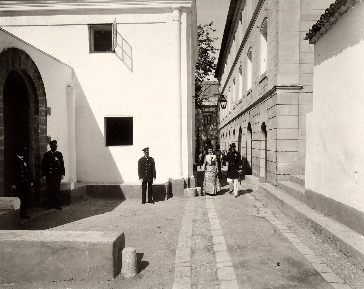 Mænd i uniform, der ledsager en elegant klædt kvinde mod kirken på gården Lo Zucco, Sicilien, 1900 af Eugenio Interguglielmi
