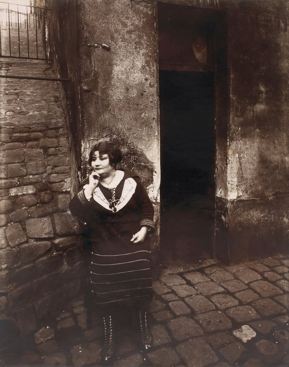 La Villette. Rue Asselin, prostitueret, der venter foran hendes dør af Eugène Atget