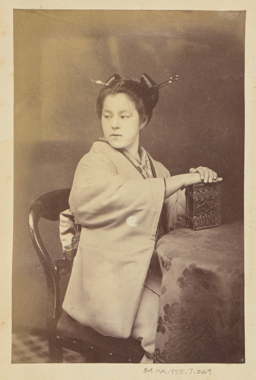 [Siddende japansk kvinde med et cartes-de-visite-album ved et bord]. af Felice Beato