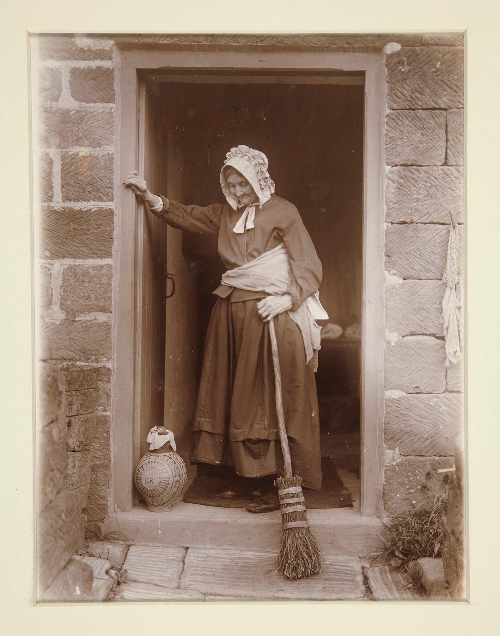 En gammel dame med en gærflaske ved en hyttedør af Frank Meadow Sutcliffe